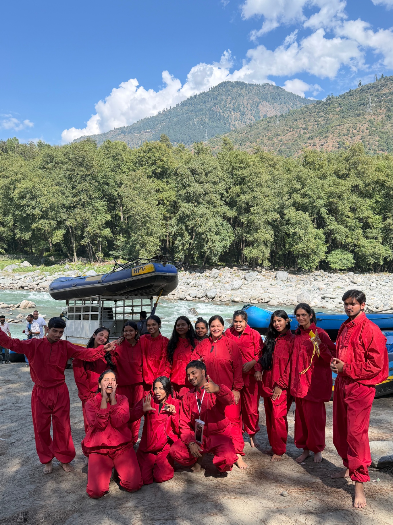 The group in red rafting suits beside the river and their raft