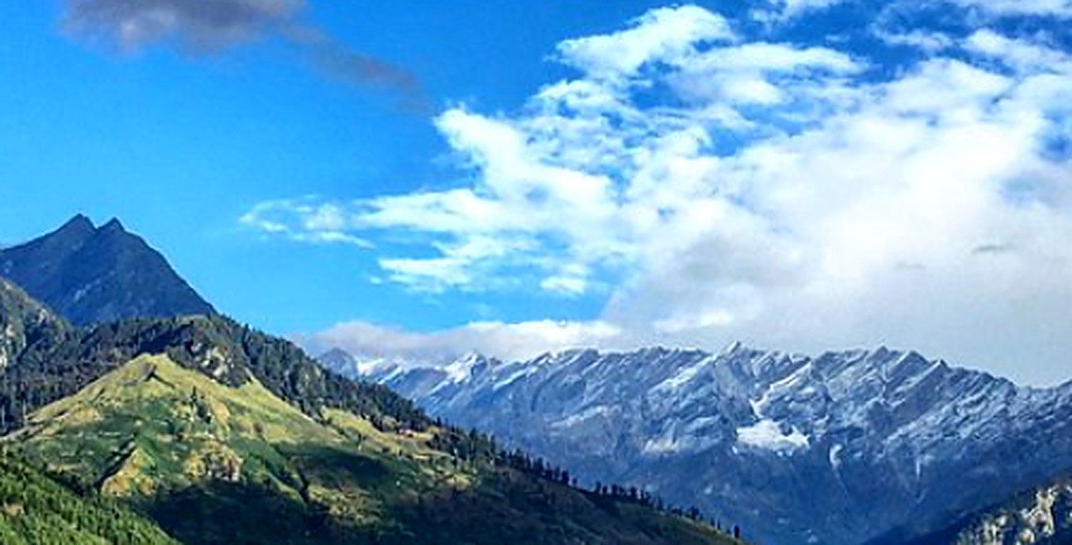 Snow-dusted Himalayan peaks above green Manali slopes