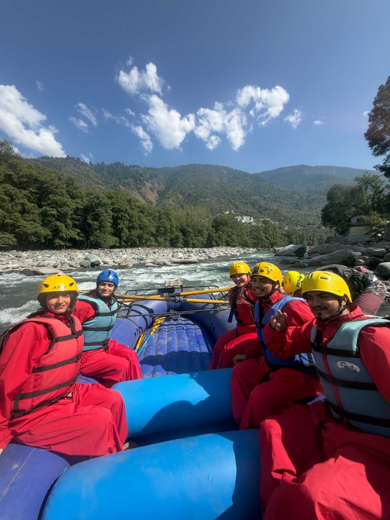 Travellers in red rafting suits and helmets on a raft in the river
